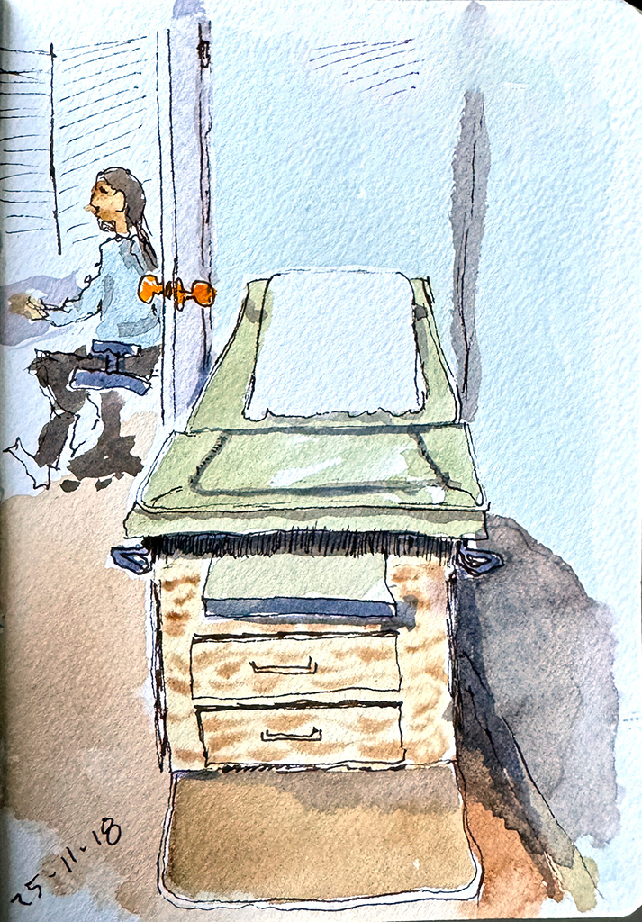 Line and wash sketch. An exam table seen from the foot end. On the back wall, an open door with a nurse working at a desk. 